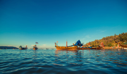 Longtale boat at the Thai beach. Paradice sand beach place. Boats on the clear water and blue sunrise sky.