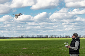 man operating of flying drone quadrocopter at the green field