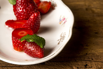 Cut strawberries and mint leaves on plate
