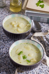 White asparagus soup with coconut milk. Stone table, gray background, books, bottles and wooden board.