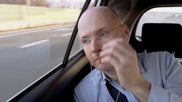 Bald Businessman in the Car Putting Glasses On