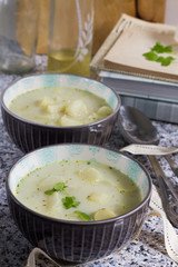 White asparagus soup with coconut milk. Stone table, gray background, books, bottles and wooden board.