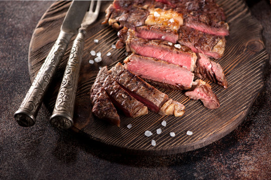 Medium rare grilled beef steak ribeye on a wooden serving board