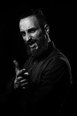 Black and white studio portrait of a handsome man with a beard in the black shirt