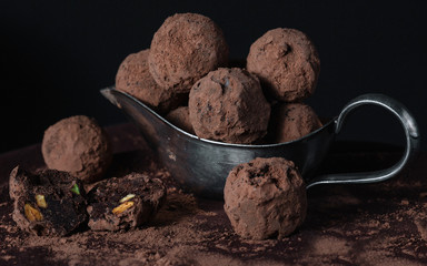 Homemade chocolate truffles in old-fashioned dish on dark background