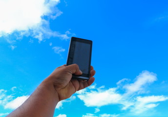 male hand holding mobile phone closeup or smartphone on blue sky background