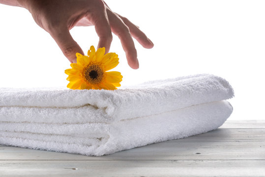 Picture of spa towel and yellow flower and the hand in the white backround.