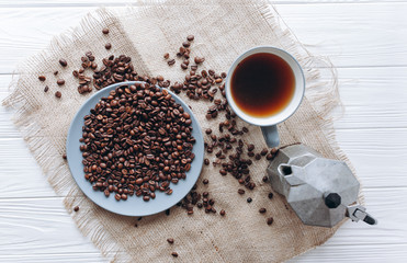 cup of coffee,coffee maker  and coffee beans on a white wooden background