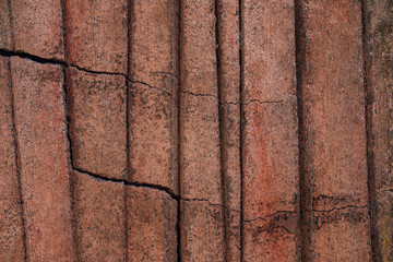 Horizontal cracks in the red wall. Stone texture with vertical grooves.