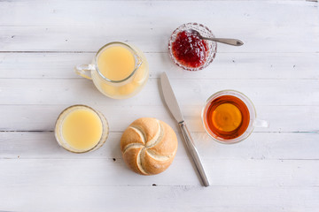 Breakfast table with fresh juice, jam, bread and tea.