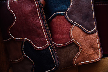 A fragment of a leather bag and a purse made of multi-colored pieces. White leather stitching.