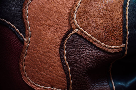 A fragment of a leather bag and a purse made of multi-colored pieces. White leather stitching.