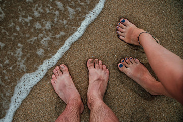 Man and woman legs on a beach in a surf.