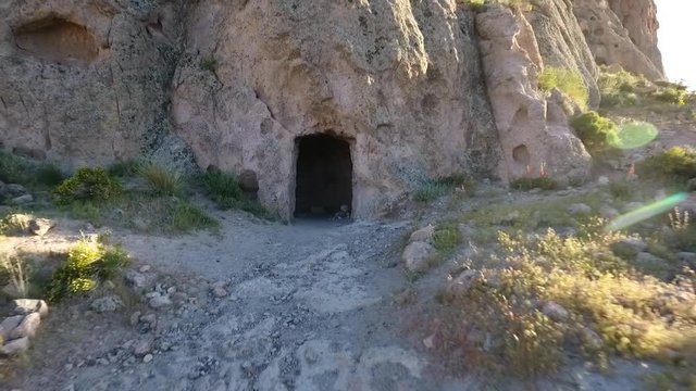 Aerial pullback of a cave or mine entrance in a towering desert cliff