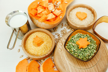 Cut Pieces of Pumpkin with Seeds,Cereals in the Wooden Plates and Pea.Milk,Harvest,Fresh Vegetable, Ingredient.White Food Background.Selective Focus