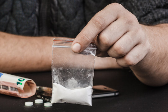 A drug addict or drug dealer holding a package of heroin or cocaine.