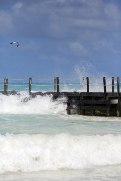 Stormy weather on the shores of the Caribbean sea. Huge waves hitting the wooden bridge.