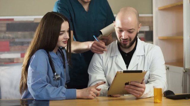Healthcare, medical: Group of doctors discussing and looking x-ray in tablet in a clinic or hospital. UHD 4K