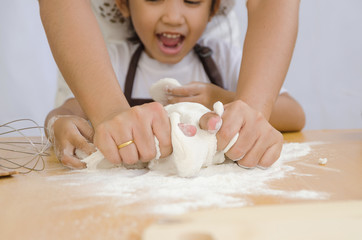 Obraz na płótnie Canvas Close up shot of Asian little girl with hands of mother kneading the dough for making the bakery