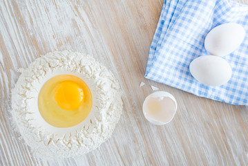 Ingredients and tools for baking - flour, eggs and glass of milk on the wooden rustic table background, selective focus