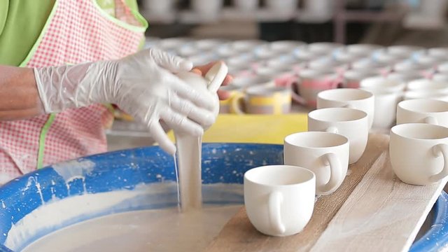 Ceramic artisan in Caltagirone submerging a bowl into enamel