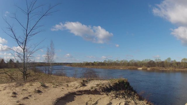 Time-lapse. Clouds are running over the river.