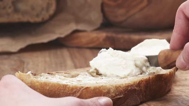 Slow motion of spreading ricotta cheese on fresh rustic bread, 180fps prores footage