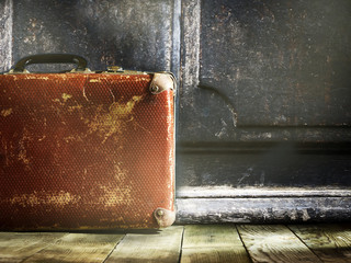 Old vintage suitcase on a wooden floor.