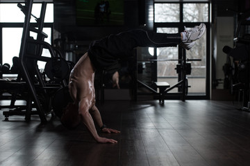 Fototapeta na wymiar Athlete Doing Extreme Handstand In Gym