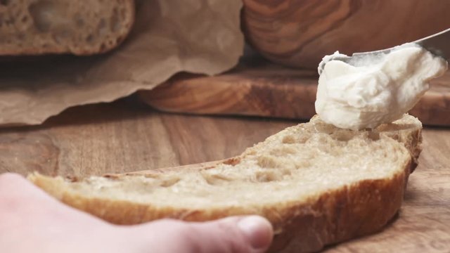 Slow motion of spreading ricotta cheese on fresh rustic bread, 180fps prores footage