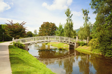 Summer park background with vintage bridge over river