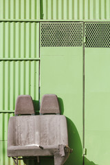 Discarded car seats in front of a green garage door