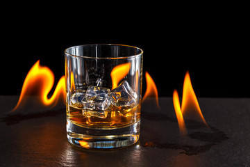 glass of whiskey with ice on a background of a burning flame