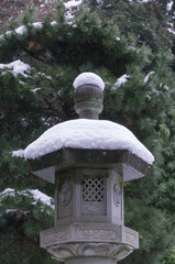 A stone lantern and moss covered with snow on top. © micromagic