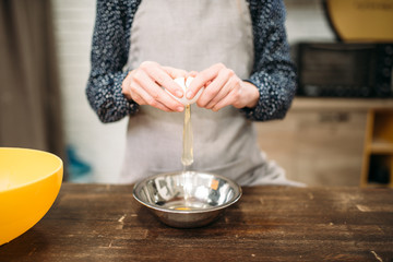 Female person breaks the egg into a bowl