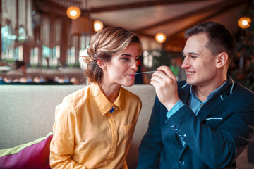 Smiling man feeding woman with spoon in restaurant