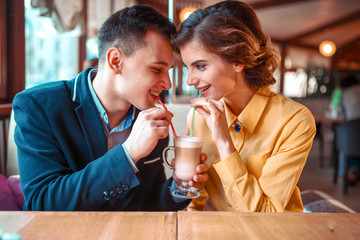 Couple drink a cocktail together from the straws