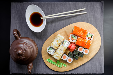 Set sushi rolls, soy sauce, teacup and chopsticks on a grey tablecloth. Top view. Flat lay. Japanese traditional food