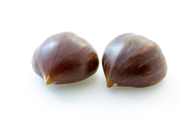 Two tasty uncooked chestnuts with white background