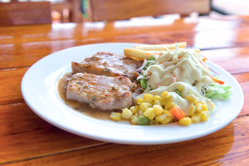 plate of grilled pork with french fries and salad