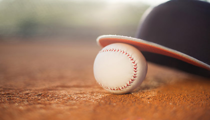 Baseball cap and baseball ball on field, copy space