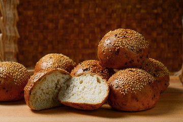 fresh wheat rolls with sesame lie on the cutting Board on the background of the basket