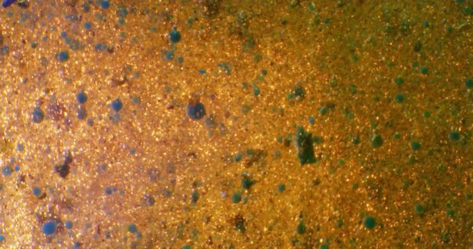 Gold Liquid. Color drops floating in oil and water over a colorful underground with oil painting effect. 4K.

