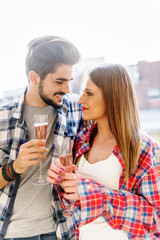 Young urban casual romantic couple on balcony with champagne