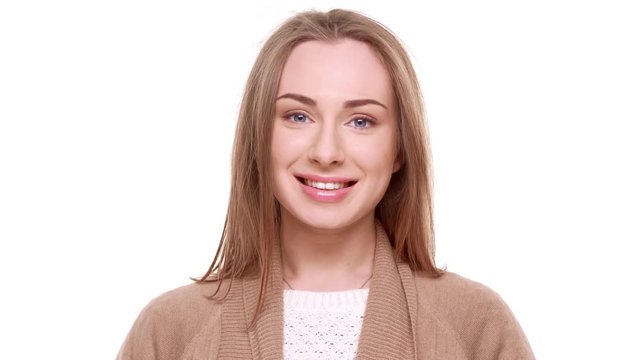 Confused Caucasian young female with light brown hair standing shy on white background