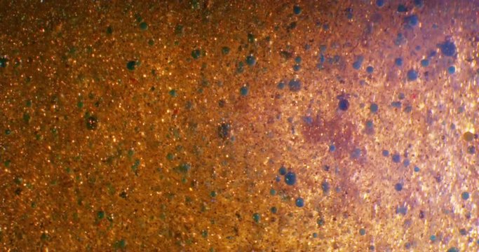 Gold Liquid. Color drops floating in oil and water over a colorful underground with oil painting effect. 4K.

