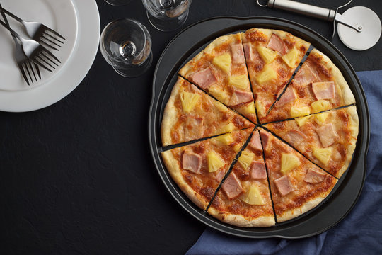 Homemade pizza hawaii fruit and meat on dark slate background with tableware.