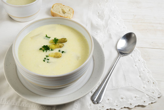 Asparagus cream soup with parsley garnish in a bowl on a white wooden table with napkin copy space, selected focus, narrow depth of field