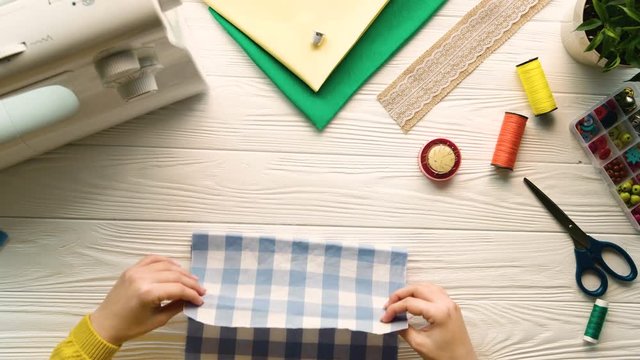Woman hands sewing cloth with needle on white designer desk. Top view. Pattern fabric cloth. Designer, tailor. Slow motion Stitching