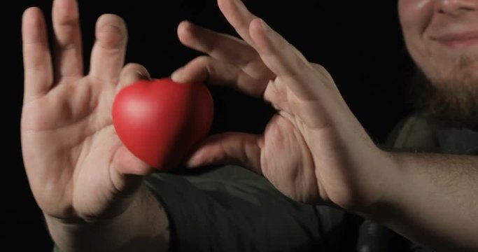 Red heart in the hands of a soldier, concept